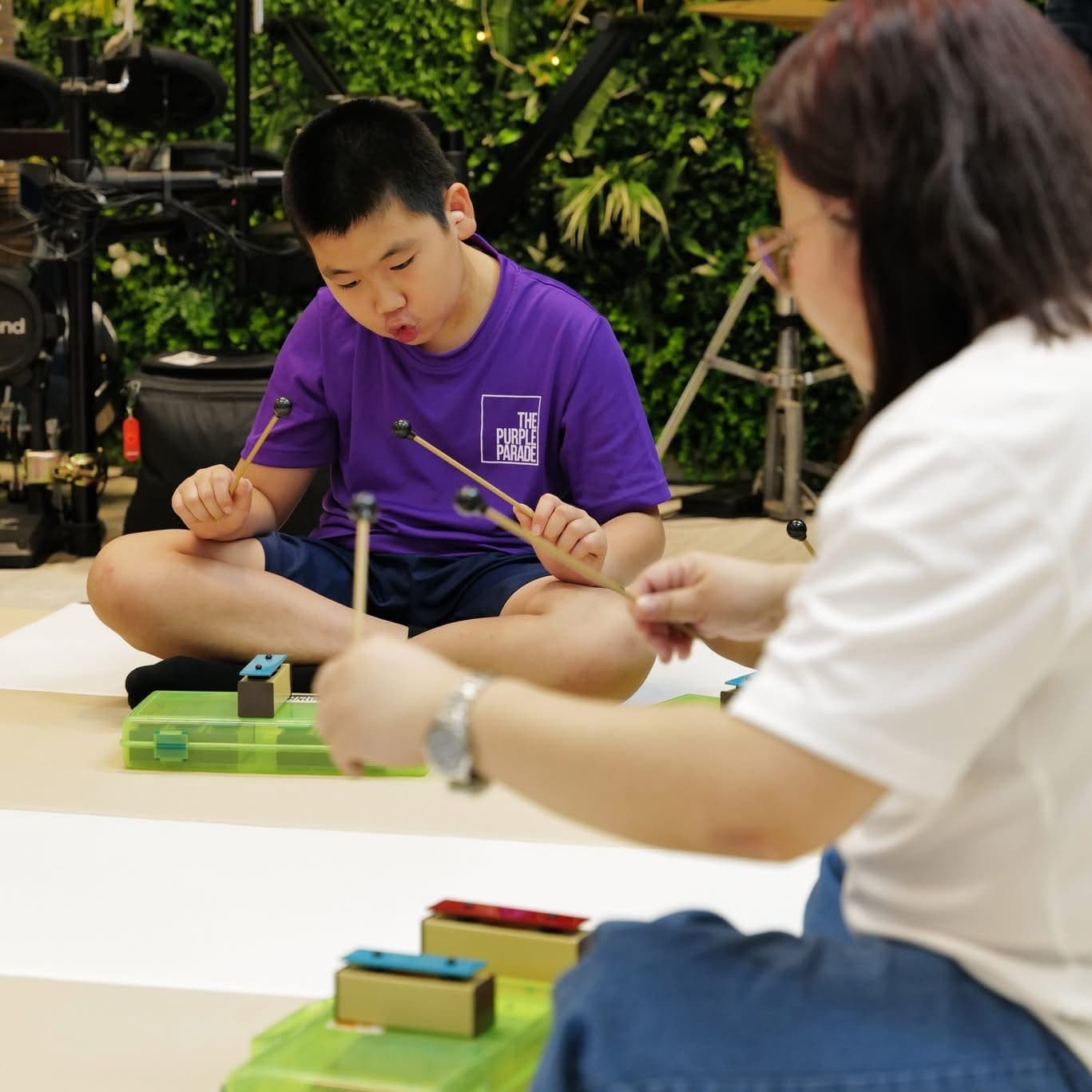 Young children sitting in a circle shaking percussion instruments during a Music & Movement class